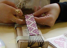 kid making beaded bracelet on cardboard loom