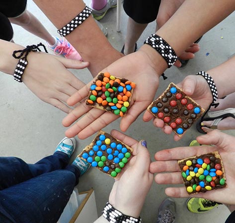kid hands holding MnMs graham crackers and wearing beaded bracelets